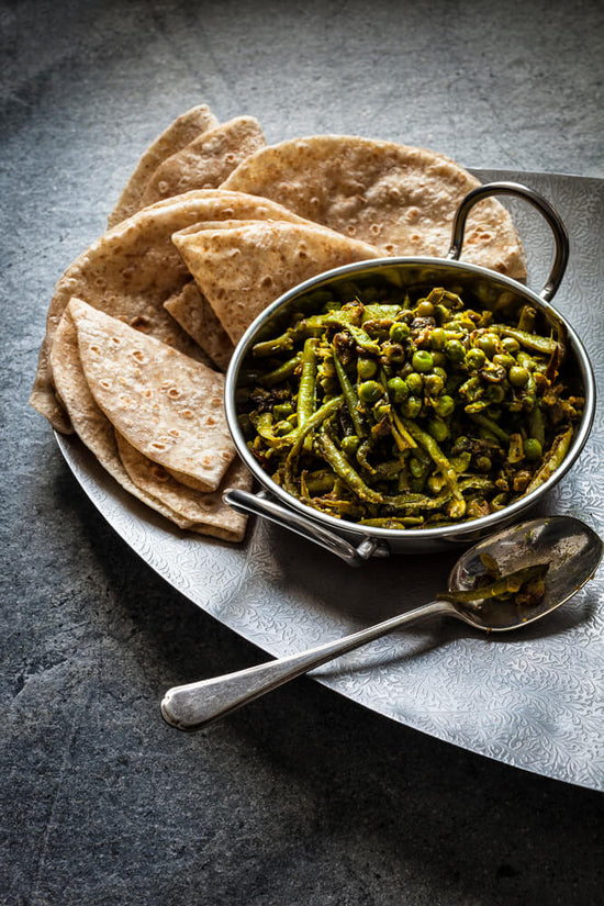 Gujarati peas nu bean nu shaak with rotli in a kadhi with a sppon served on silver tray