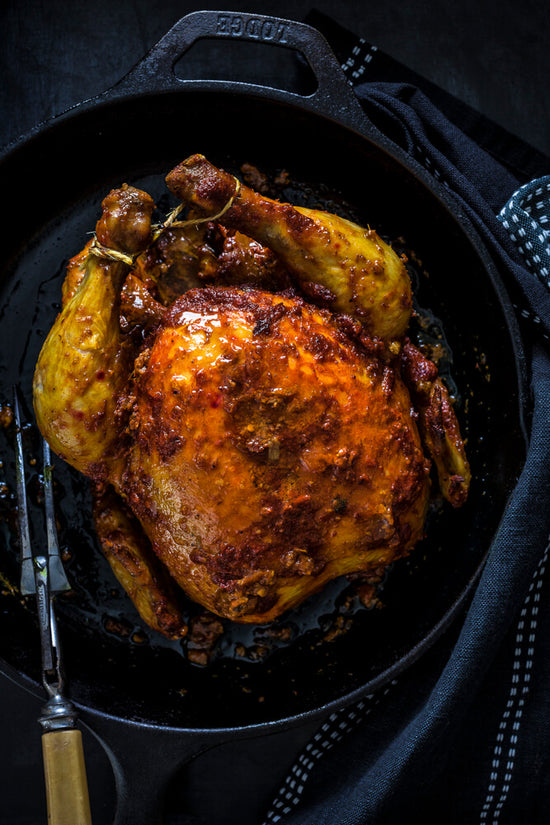 Masala Roast chicken with baked on spices inside a roasting dish ready to eat