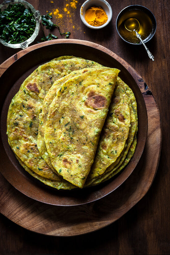Thepla, a pile of Fenugreek (methi bhaji) rotli on plate, top thepla folded