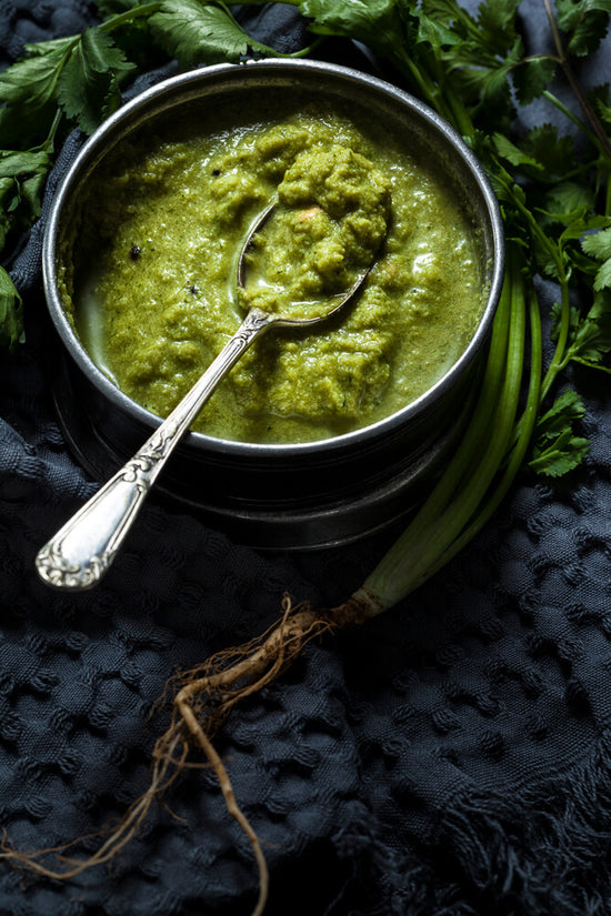 Dhania ne chutney is a coriander chutney in a bowl with spoon, fresh coriander and roots