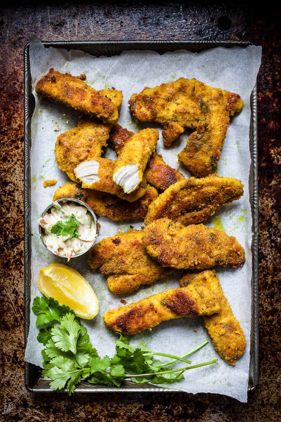 masala marinated breaded, crumbed chicken pieces on a tray served with raita