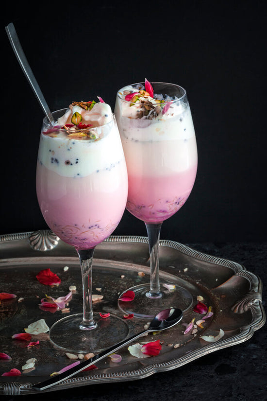 Falooda in two wine glasses decorative with rose petals and spoon