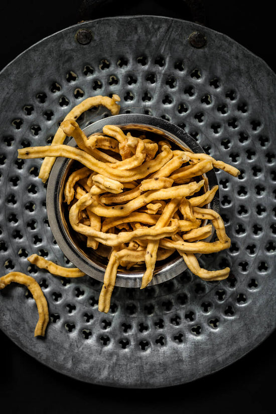 Gujarati style Ganthiya in a bowl sitting on a gathiya jarda