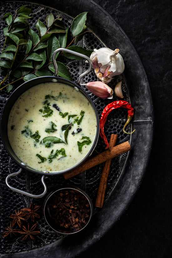 Gujarati Kadhi on tray with curry leave, garlic, chilli, star anise, cloves, chilli