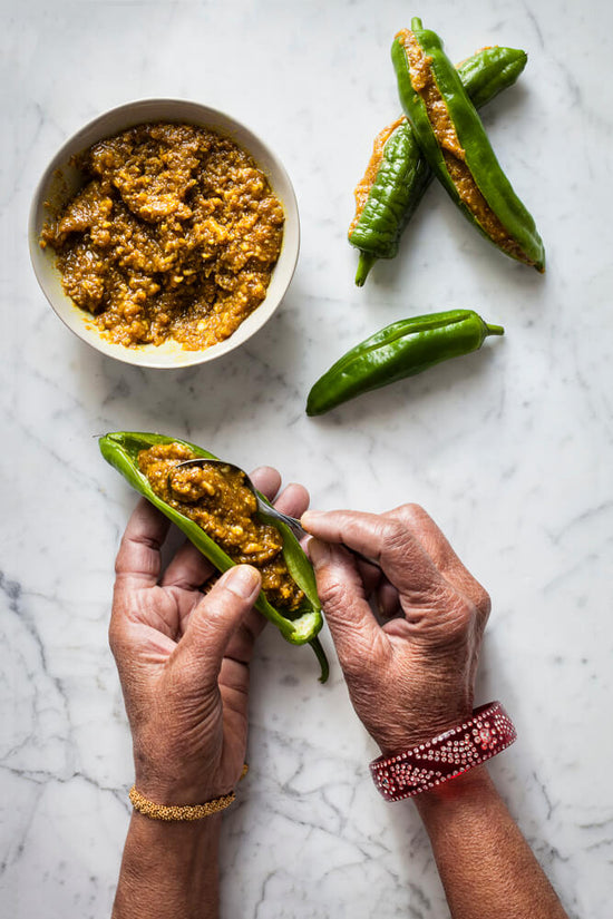 mother's hand filling chillies with masala mixture for macha na raveya