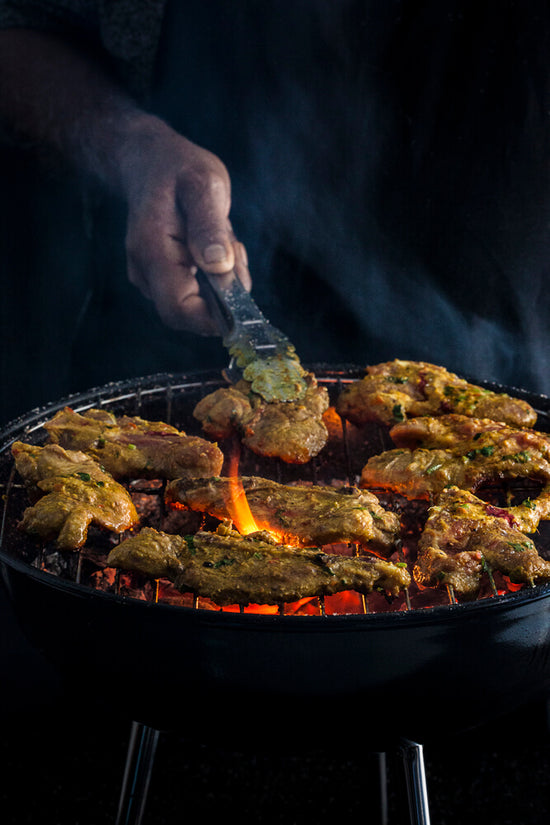 Masala chop on charcoal barbeque, BBQ with hands and tong and flame.