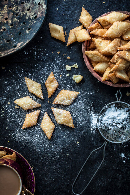 Sarkarpada in a star shape with chai and chai strainer and icing sugar